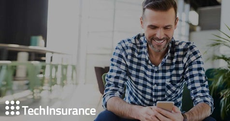 Businessman smiling while holding phone.