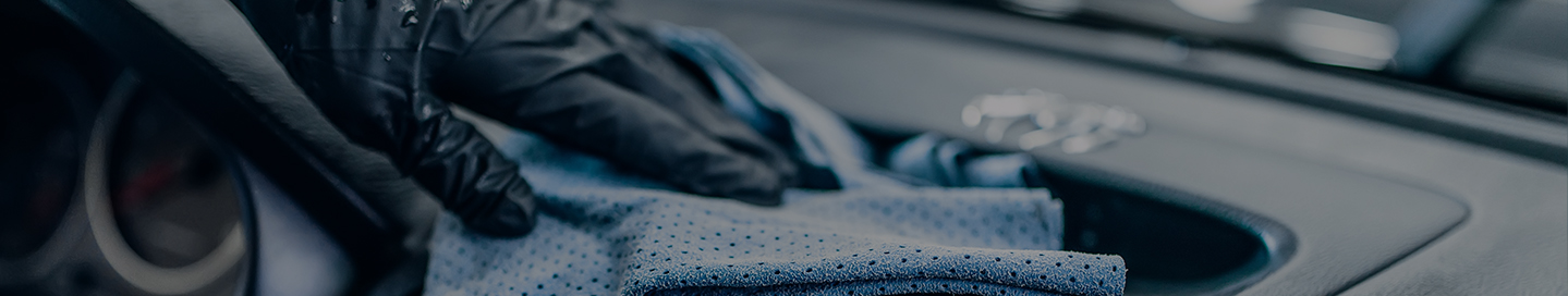 An auto detailing employee cleans the dashboard of a customer's car. An auto detailing employee cleans the dashboard of a customer's car.
