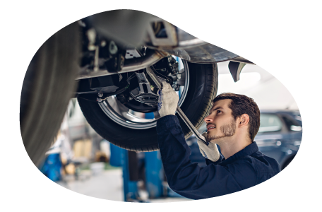 A mechanic works on a customer's car elevated on a lift.