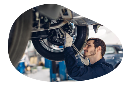 A mechanic works on a customer's car elevated on a lift. A mechanic works on a customer's car elevated on a lift.