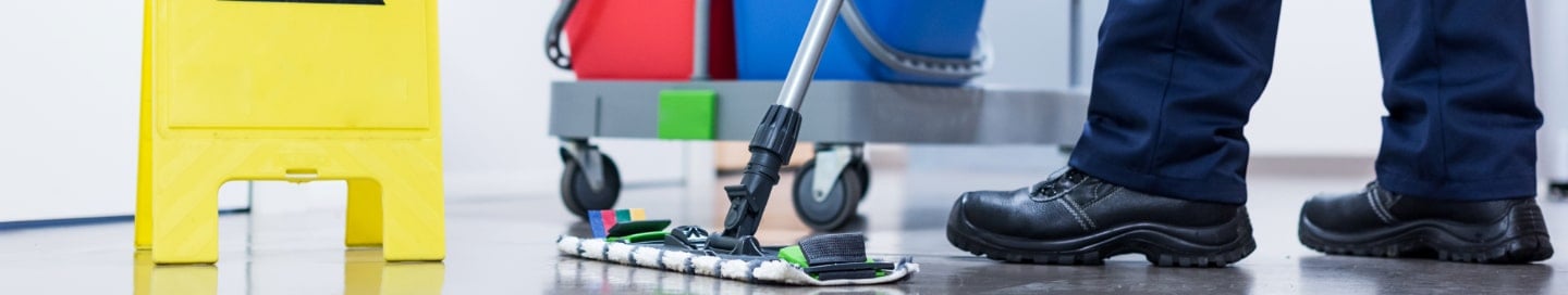 An employee at a cleaning business mops a client's floor. An employee at a cleaning business mops a client's floor.