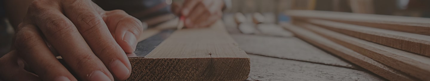 A carpenter measuring a piece of hardwood on-site.