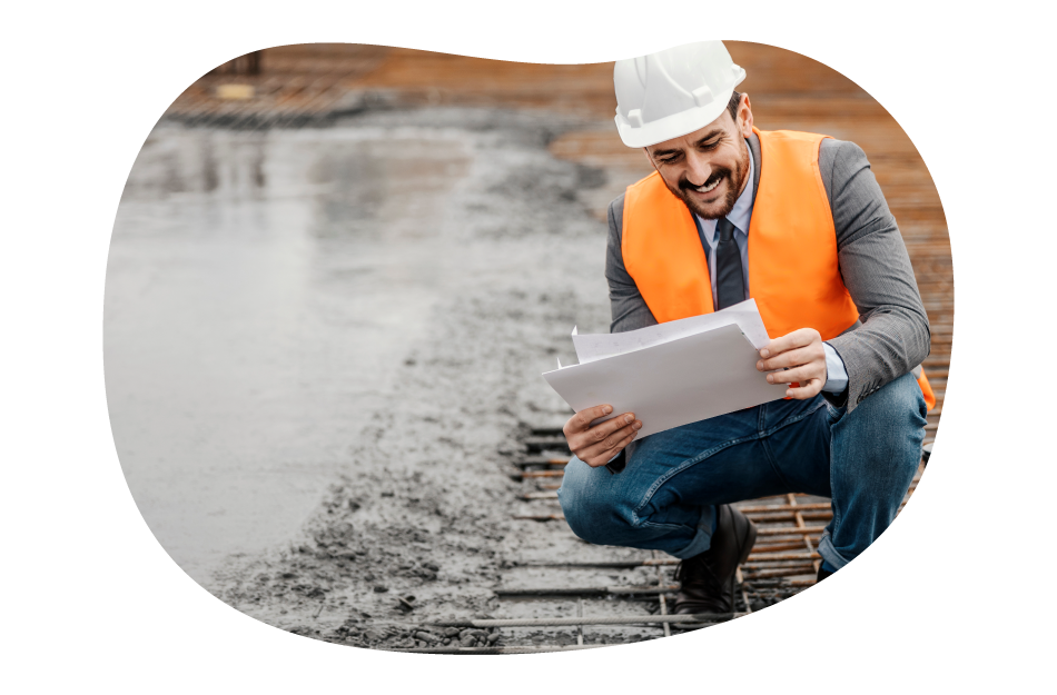 A contractor examines plans by wet concrete. A contractor examines plans by wet concrete.
