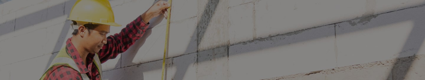 Construction worker measuring a building exterior.