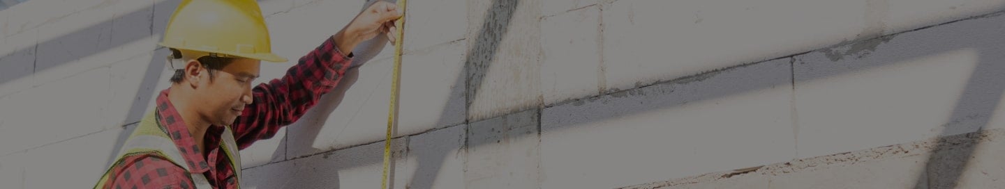Construction worker measuring a building exterior. Construction worker measuring a building exterior.