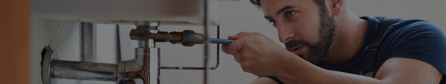 A plumber tightens a pipe with a wrench. A plumber tightens a pipe with a wrench.