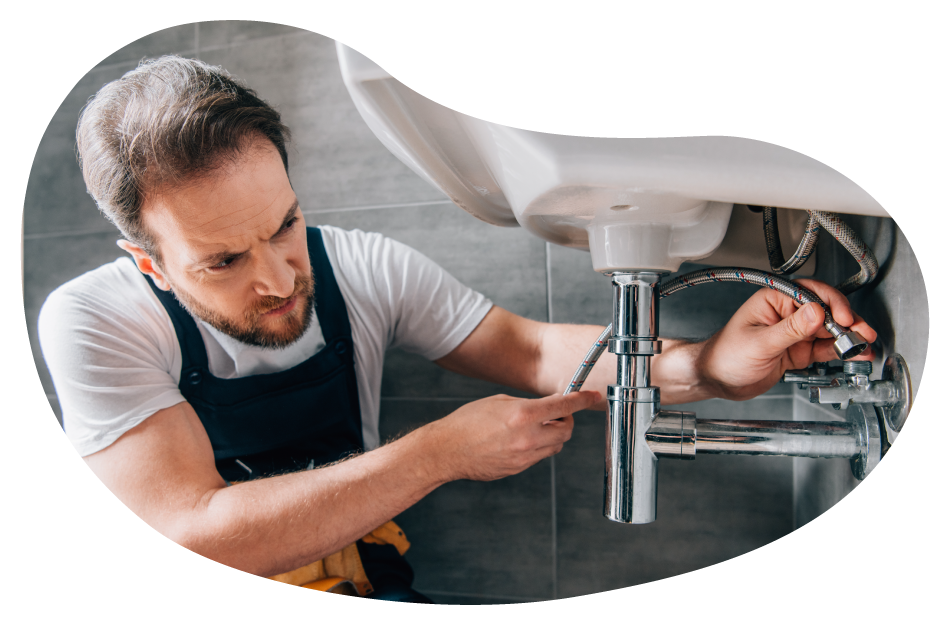 A plumber attaches a water line underneath a sink. A plumber attaches a water line underneath a sink.