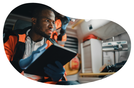 An EMS professional documenting notes on their tablet as they look after a patient 