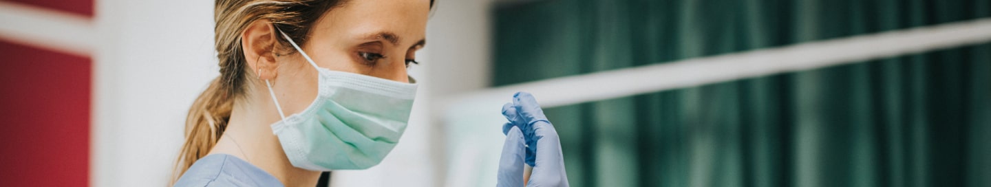 A nurse in a hospital putting on gloves.
