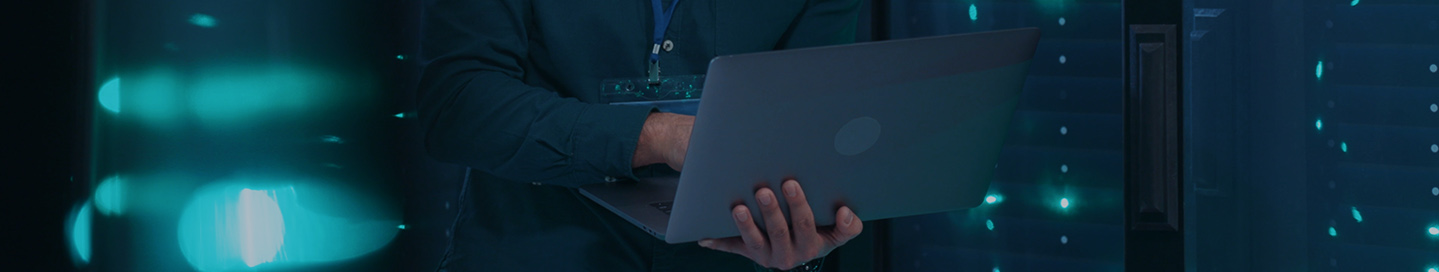 Technician working on a laptop inside a cloud computing server room. Technician working on a laptop inside a cloud computing server room.