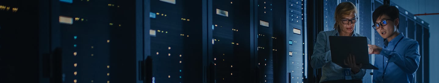 Two people looking at laptop in data center. Two people looking at laptop in data center.