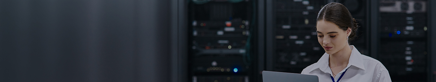 Person looking at laptop in a data center.