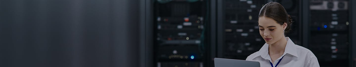 Person looking at laptop in a data center.