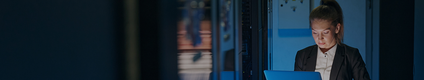 Employee working on a laptop in an SaaS server room.