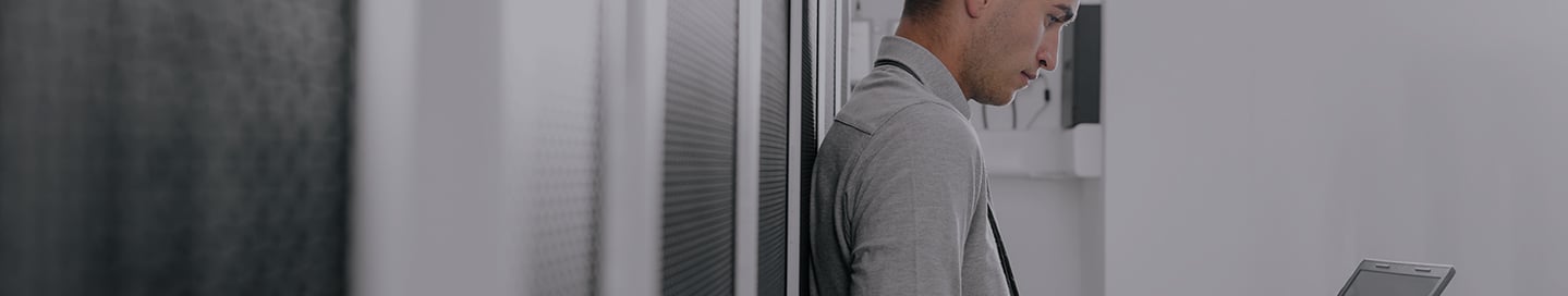 Employee working on a laptop in an SaaS server room. Employee working on a laptop in an SaaS server room.