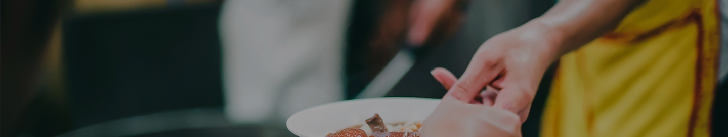A volunteer serves a meal at a soup kitchen.