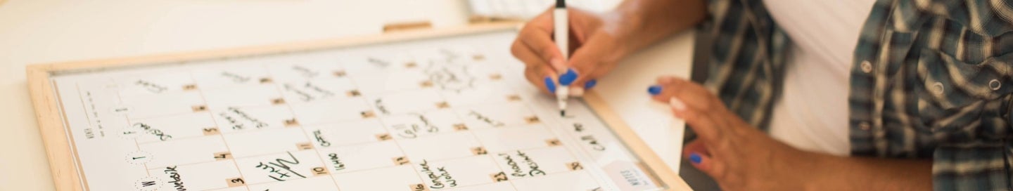 An event planner writing out a schedule on a whiteboard. An event planner writing out a schedule on a whiteboard.