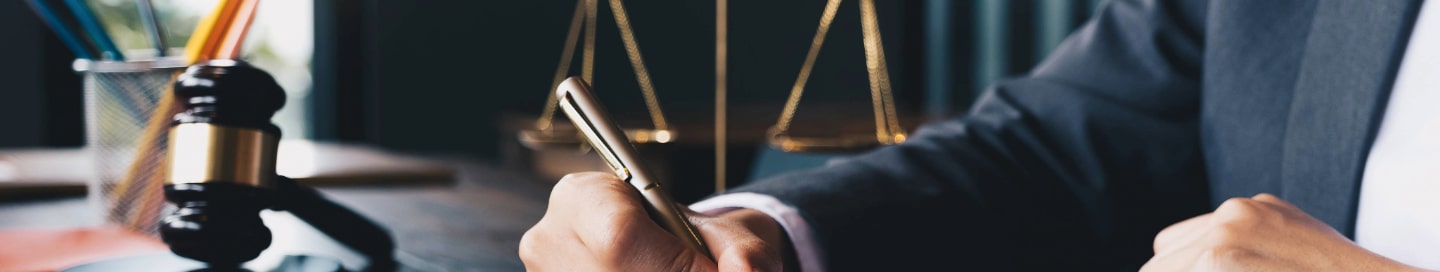 A lawyer writing in a notebook next to a gavel and scales.
