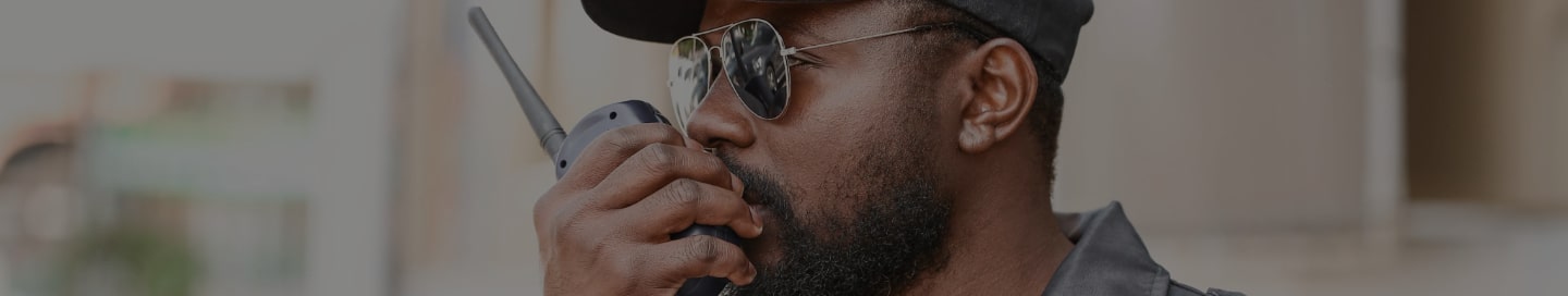 Security guard speaking into walkie talkie.