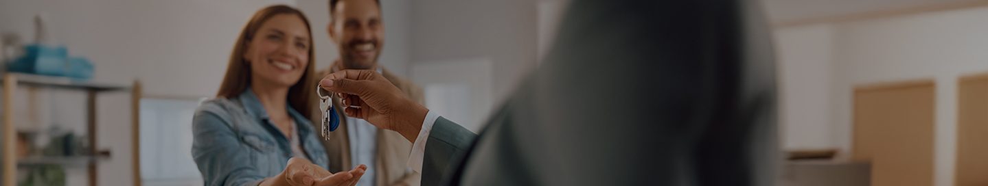 A real estate agent handing a key to a new homeowner.