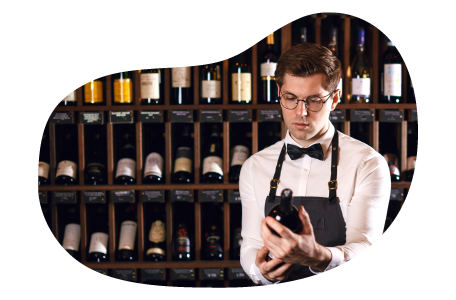 The owner of a liquor store inspects a bottle of wine. The owner of a liquor store inspects a bottle of wine.