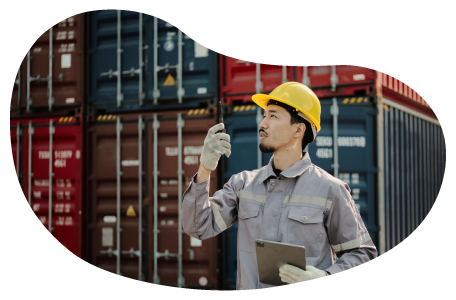 A freight forwarder makes a call in front of shipping containers.