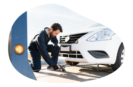 A towing company employee secures a car with a tow chain and hook.