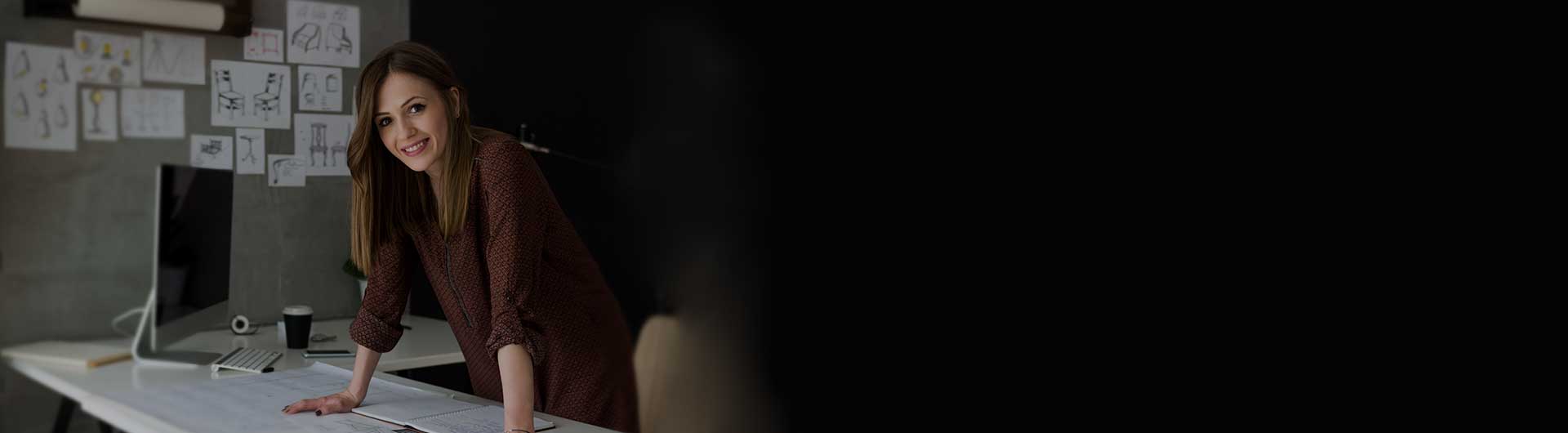 Woman smiling and leaning on desk.
