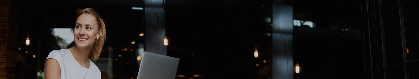 Person with blond hair smiling while on a laptop.