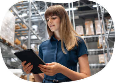 A small business owner using a tablet in warehouse surrounded by shelves of boxes. A small business owner using a tablet in warehouse surrounded by shelves of boxes.