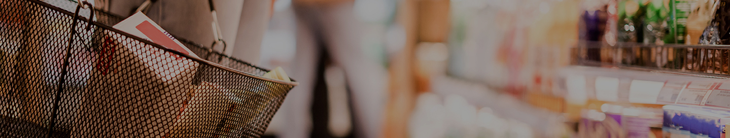 A shopper with a hand basket in a grocery store.