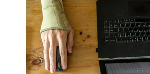 Person with arm in wrist brace using a mouse and laptop